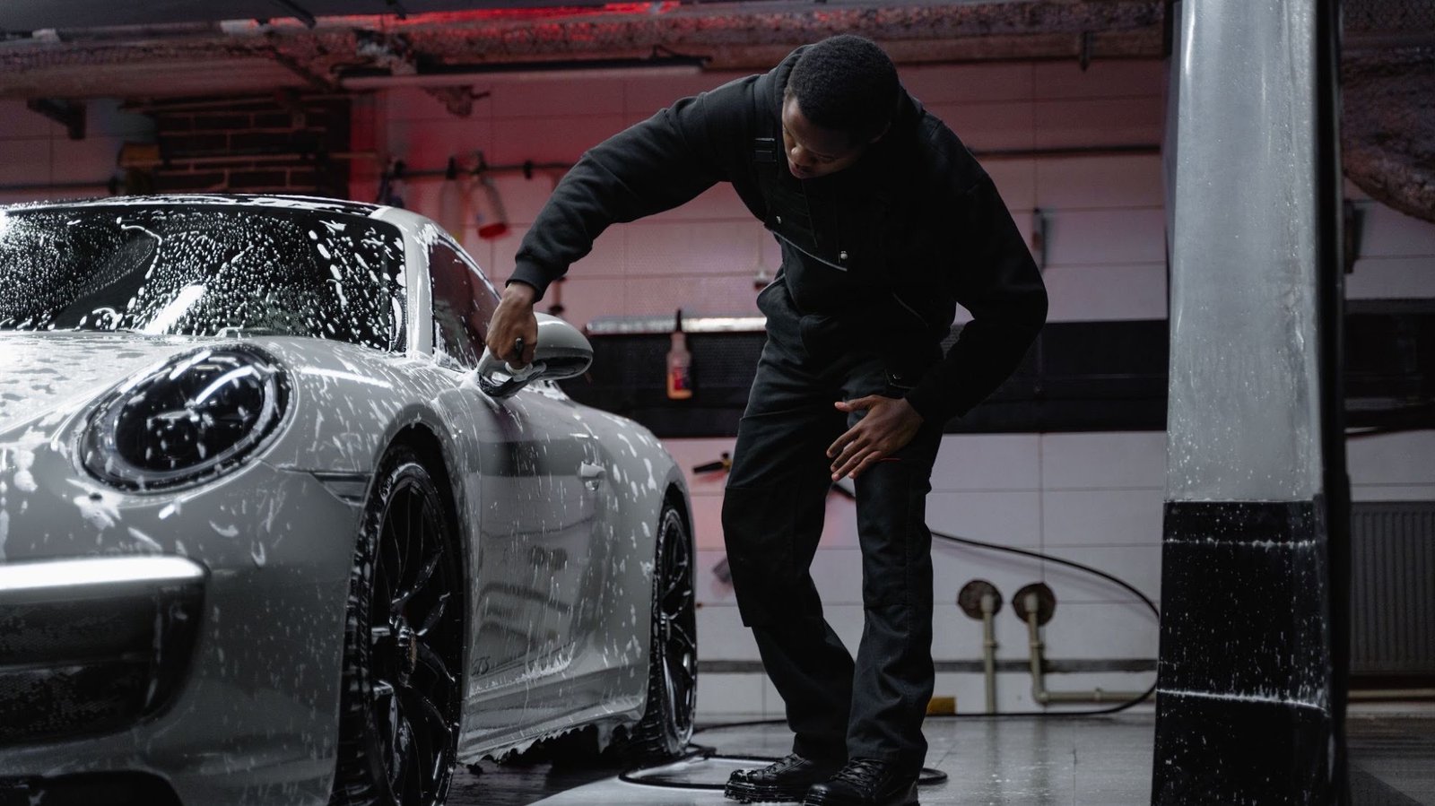 Car covered in snow foam being washed by hand